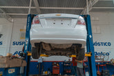 A white Chevrolet car is lifted for maintenance in an automotive repair shop.