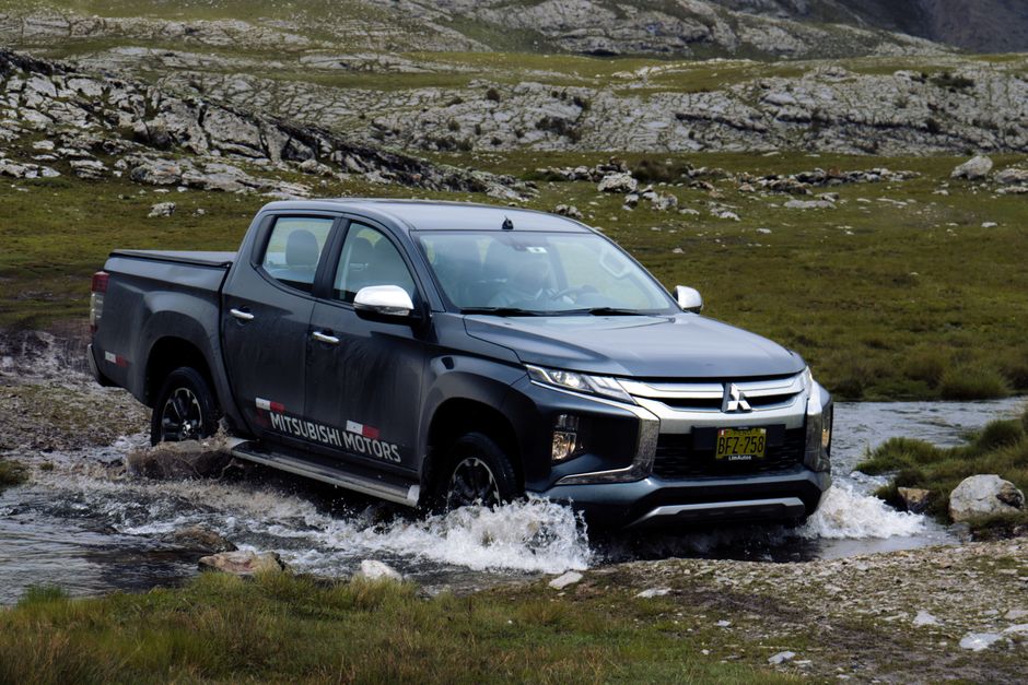 Mitsubishi Triton pickup truck navigating a rocky stream, showcasing power and ruggedness.
