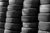 Black and white image of stacked vehicle tires showcasing various tread patterns.